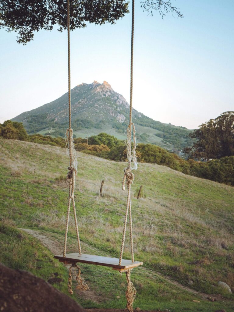 Eine Schaukel im Grünen, dahinter ein Bergkegel unter blauem Himmel: ein Moment zum Innehalten.